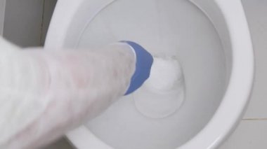 Koruyucu giysiler giyen, tuvalette dezenfekte eden, bir klozetin içini dezenfektanla temizleyen...