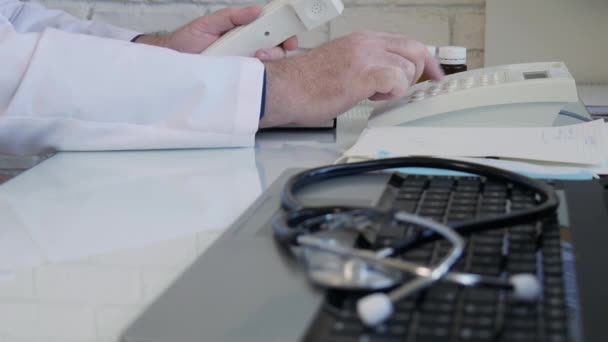Zeitlupe mit einem Arzt im Krankenhausbüro, der eine Telefonnummer über das Festnetz wählt, ein Arzt, der im medizinischen Kabinett telefoniert — Stockvideo