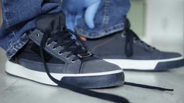 Homem se preparando para uma caminhada amarrando as cadeias aos seus sapatos esportivos usando luvas de proteção — Vídeo de Stock