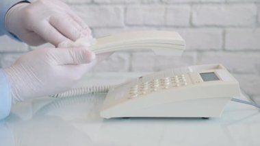 Ellerinde koruma eldivenleri olan, sprey ve ıslak mendil kullanarak telefonu temizleyen ve dezenfekte eden bir adamla Yavaş Hareket