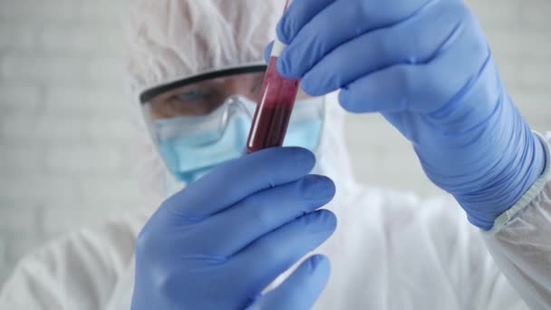 Медленное движение с врачом в больничной лаборатории в защитном костюме, смотрящим на трубу с зараженной коронавирусом кровью — стоковое видео