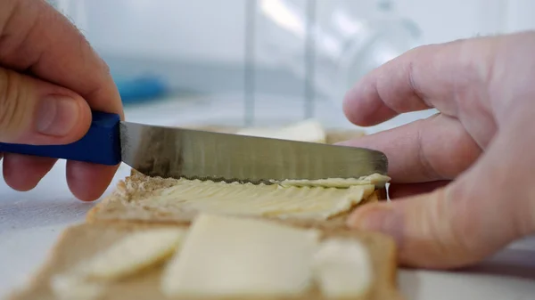 Frühstück mit Butter auf dem Toast, Margarine auf einer frischen Scheibe Brot in der Küche verteilen — Stockfoto