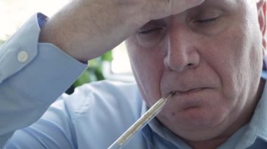 Coronavirus semptomları gösteren bir adam bir hastanede vücut ısısını ölçmek için civa ölçeğinde termometre kullanıyor.