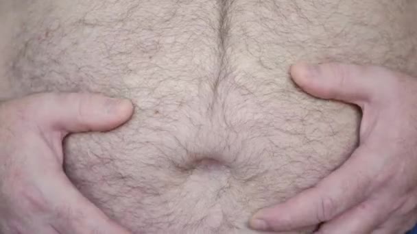 Fettleibiger Mann zeigt seinen dicken Bauch, ein Hungriger misst sein Bauchfett mit den Händen, Gesundheitsprobleme eines alten Mannes mit Fettleibigkeit — Stockvideo