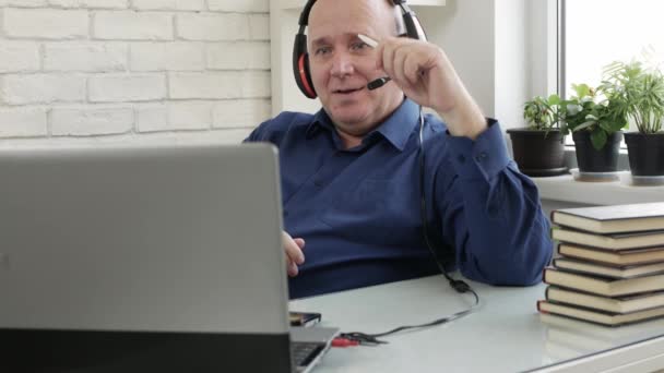 Человек, работающий из дома и разговаривающий в видеозвонке с помощью веб-камеры ноутбука и наушников, социальное удаление в пандемии Covid-19, удаленная работа из дома — стоковое видео