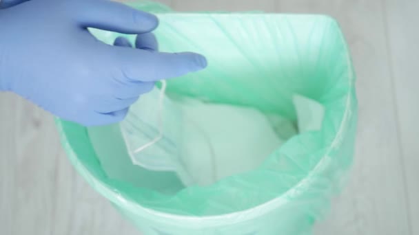 Доктор викидає сміття у повільні рукавички та маску, що використовуються та забруднюються після закінчення зміщення служби лікарні — стокове відео