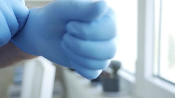 Slow Motion con un uomo che fissa i guanti di protezione della sua mano contro la contaminazione con Covid-19, stile di vita socialmente distanziato — Video Stock