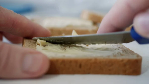 Café da manhã com manteiga no brinde, espalhando margarina em uma fatia fresca de pão na cozinha — Fotografia de Stock