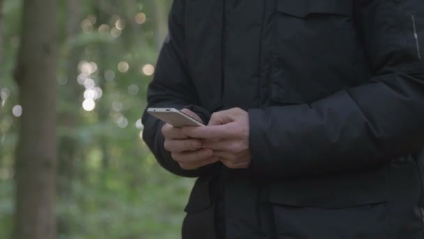 Mann schreibt SMS im Wald — Stockvideo