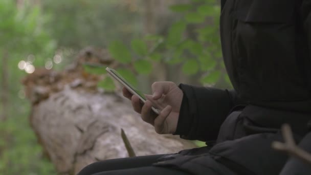 Mann schreibt SMS im Wald — Stockvideo