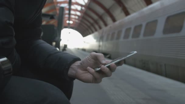 Close-up de um homem usando telefone inteligente na estação de trem — Vídeo de Stock