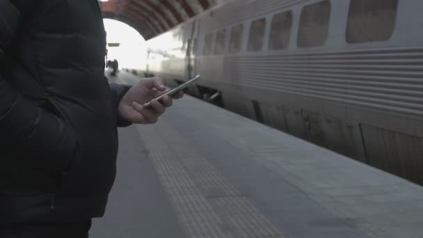 Close-up of a man using smart phone at train station — Stockvideo