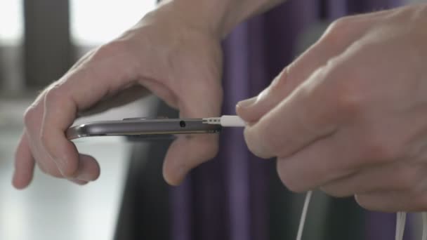 Man inpluggen in de draad naar de hoofdtelefoonaansluiting op een smartphone — Stockvideo