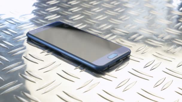 Smartphone deitado em uma placa de metal — Vídeo de Stock