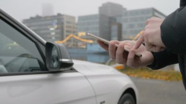 Bir adam onun smartphone arabada yağmurlu bir günde kullanır