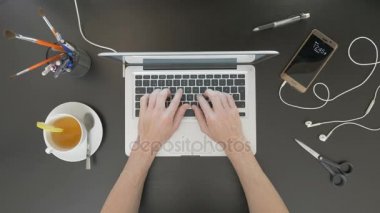 Üstten Görünüm masa. Adam onun dizüstü bilgisayarda yazarak.