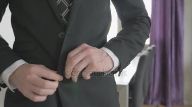 Beyaz gömlekli bir iş adamı ceketini ilikliyor.