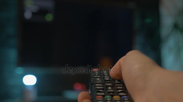 Close-up van man hand houden van de afstandsbediening van de Tv en het veranderen van kanalen. — Stockvideo