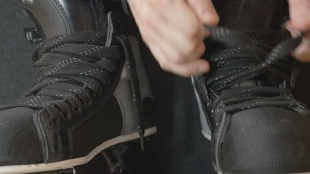 Hockey player tightening laces on his skates — Stock Video