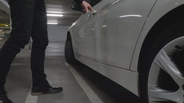 Man får i en bil parkerad i ett garage — Stockvideo