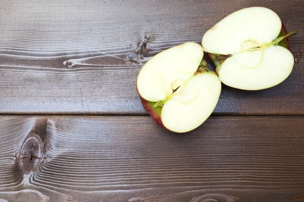 Two halves apple , pieces of a red apple on the table, red apples on a brown background. — Stock Photo, Image