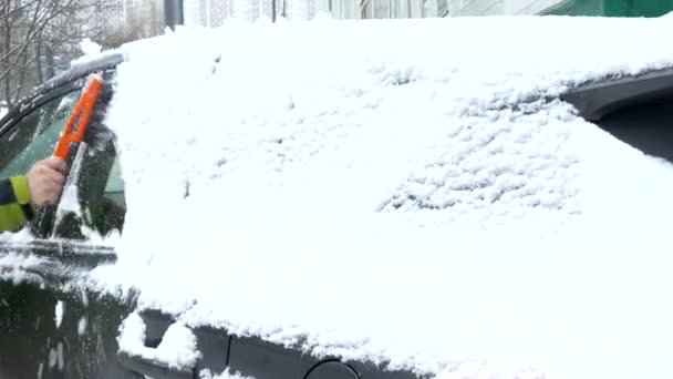 Manusia salju bersih dari kaca depan mobil setelah hujan salju lebat . — Stok Video