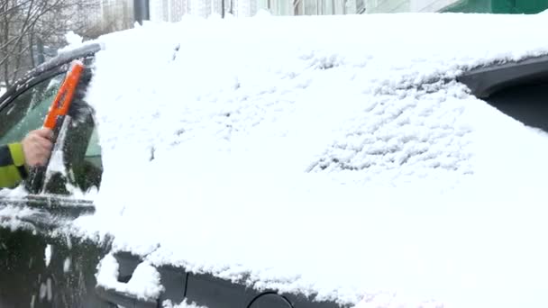 Man clean snow from car windshield after heavy snowfall. — Stock Video