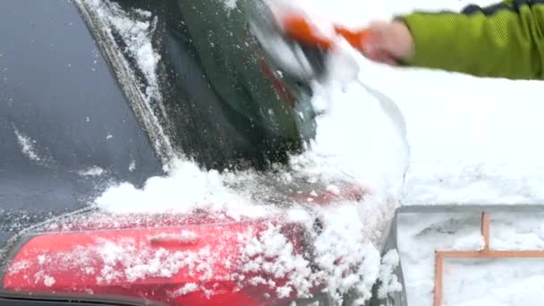 Man clean snow from car windshield after heavy snowfall. — Stock Video