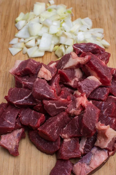 Świeże, surowe mięso posiekanej wołowiny i posiekaną cebula biała na drewnianą deską do krojenia. — Zdjęcie stockowe