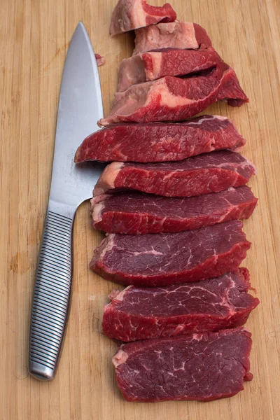 Świeże surowe mięso wołowiny w plasterki na drewnianej deski do krojenia. — Zdjęcie stockowe