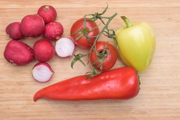 Κόκκινο Νωπά Ρεπάνι, ντομάτα, πράσινη και κόκκινη πιπεριά στην πλακέτα ξύλινη κουζίνα — Φωτογραφία Αρχείου