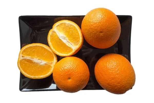 Arancio fresco su piastra nera su sfondo bianco — Foto Stock