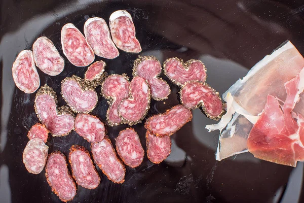 Salchicha en rodajas con especias en plato negro — Foto de Stock