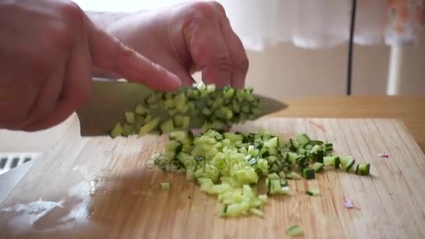 Skivning gurka i små bitar på en träskiva. — Stockvideo