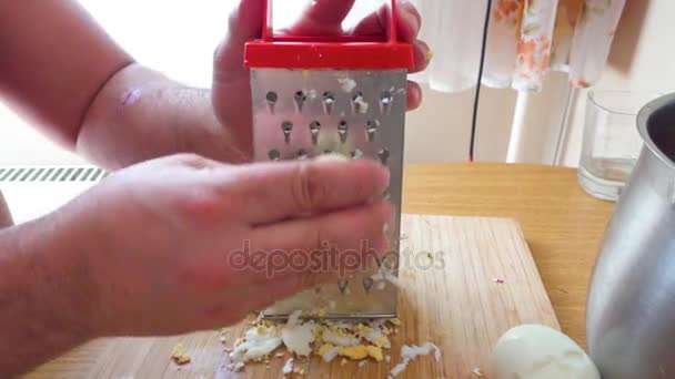 Třel si vejce na kovové struhadlo v kuchyni — Stock video