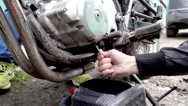 Гонщик откручивает гайки для замены масла мото — стоковое видео