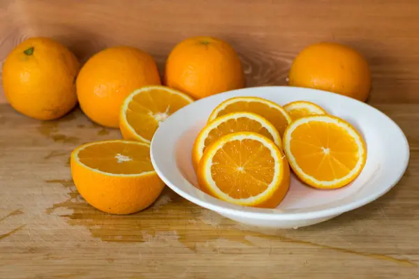 Апельсины на столе и на белой тарелке — стоковое фото