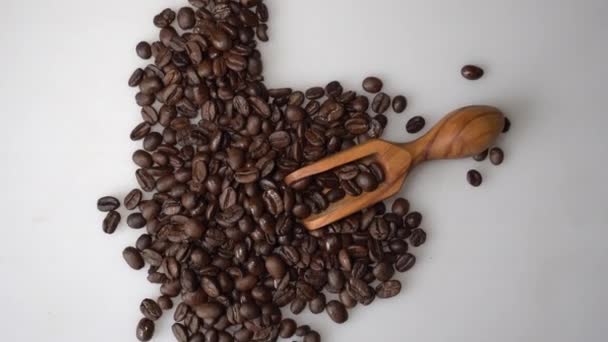 Kaffeebohnen und Olivenholz Schaufel auf weißem Hintergrund — Stockvideo