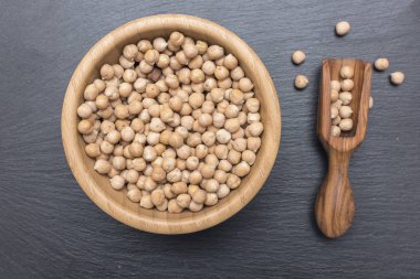 Nohut ve zeytin ahşap Kepçe bir ahşap fincan siyah arka plan üzerine kayrak veya taş