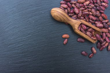 Organik Kuru fasulye ve kayrak veya taş siyah arka plan üzerine zeytin ahşap Kepçe