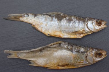 İki tuzlu roach kayrak veya taş siyah arka plan üzerine kurutulmuş.