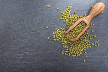 Yeşil mung fasulye ve kayrak veya taş siyah arka plan üzerine zeytin ahşap Kepçe.