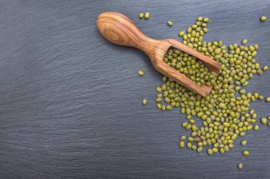 Yeşil mung fasulye ve kayrak veya taş siyah arka plan üzerine zeytin ahşap Kepçe.