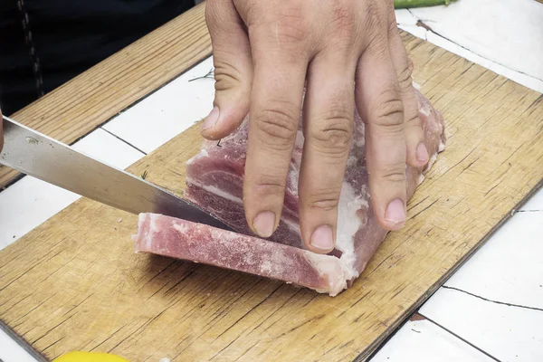 Cortar un trozo de carne en una tabla de cortar de madera — Foto de Stock