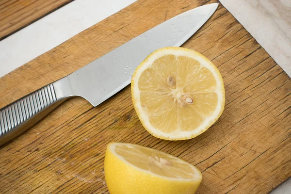 Дві половинки лимонного і сталевого ножа на дерев'яній обробній дошці — стокове фото