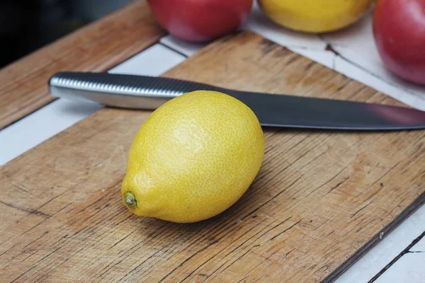 Желтый лимон на деревянном столе и стальном ноже . — стоковое фото
