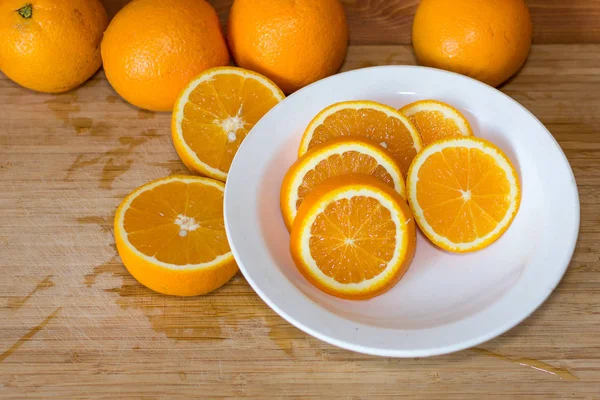 Апельсины на столе и на белой тарелке — стоковое фото