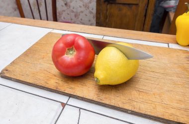 Sarı taze limon, kırmızı domates ve ahşap kesme tahtası üzerinde çelik bıçak