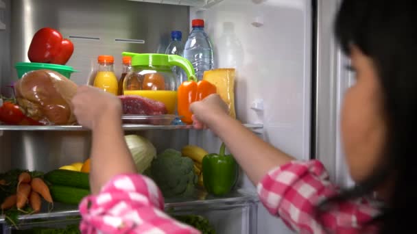 Женщина берет мясо из холодильника — стоковое видео