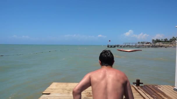 Joven Hombre Huye Durante Salto Muelle Mar Muestra Como Extremadamente — Vídeos de Stock